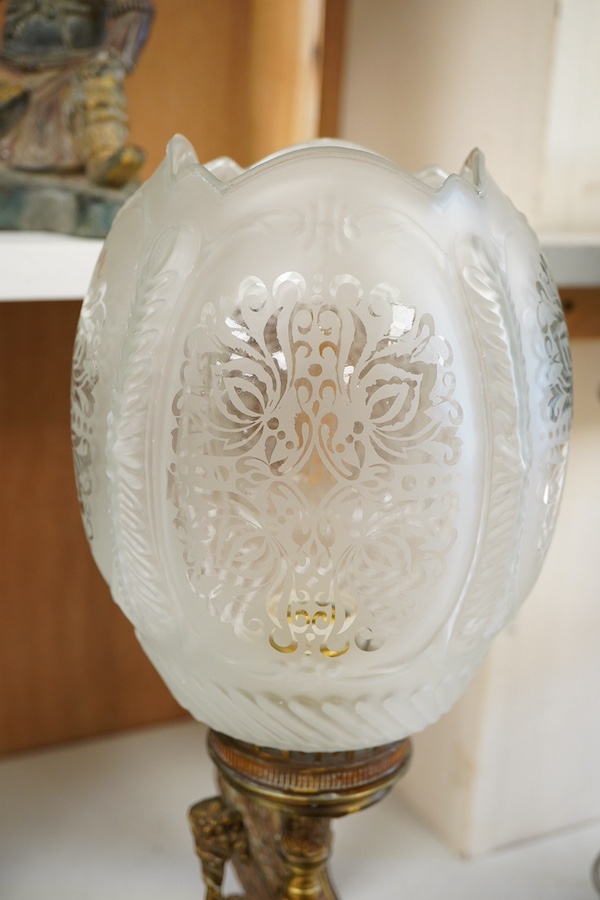 A brass three light table lamp with green toleware shade, another similar table lamp and a brass glass shaded lamp with a putti riding on the back of an eagle, (3)